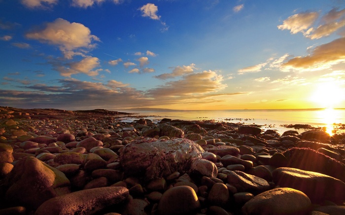 Rocky beach at sunset with ocean and clouds