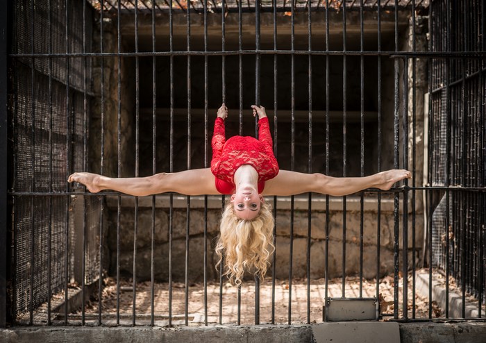Woman in red leotard doing a split upside down