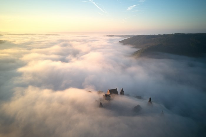 Castle emerging from fog at sunrise