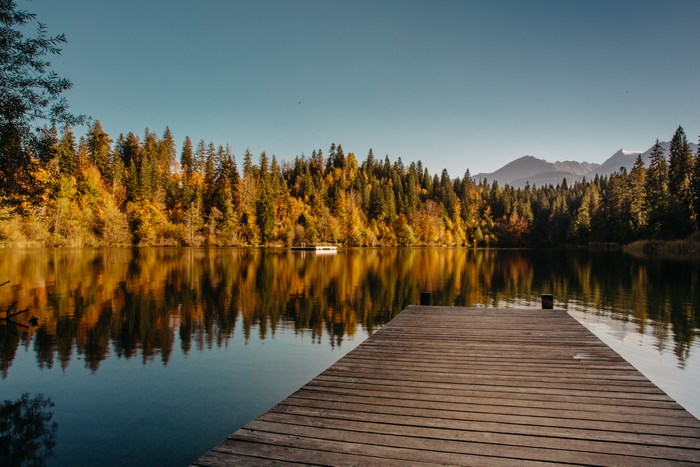 Wooden pier on a lake with autumn forest and mountains