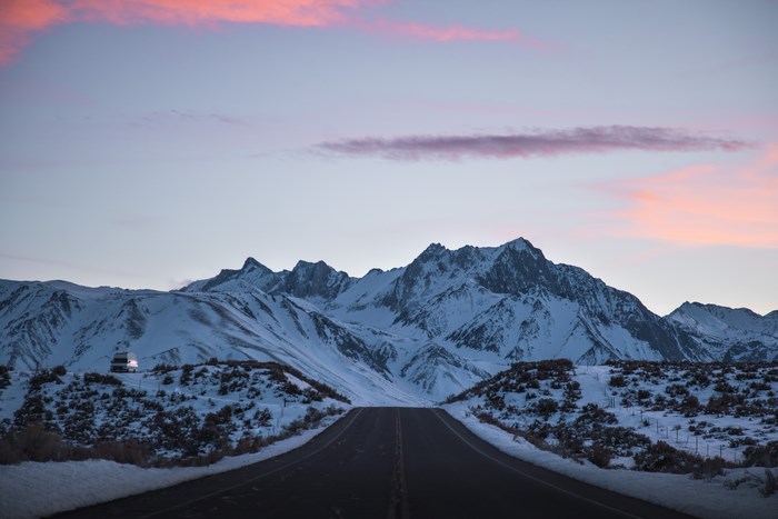 Snowy Eastern Sierras mountain range at sunset with a road
