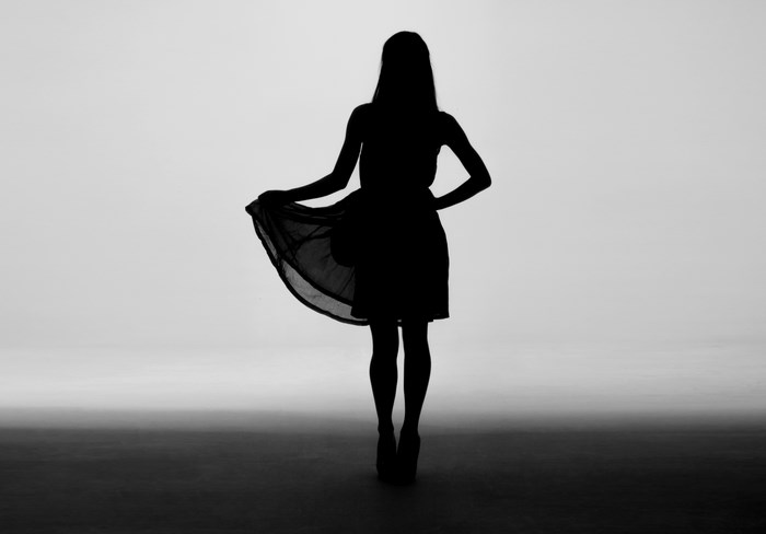 Silhouette of a woman in a dress holding her skirt
