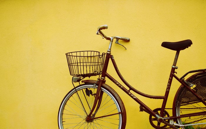 Vintage bicycle with basket against yellow wall