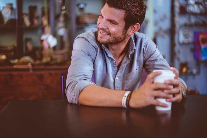 Man in blue shirt holding coffee cup at table