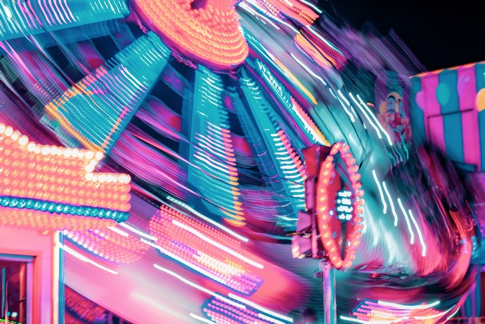 Blurry amusement park ride with neon lights at night