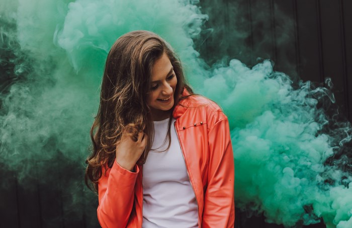 Woman in orange jacket with green smoke