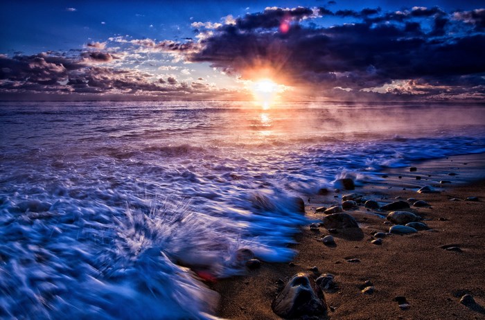 Ocean waves crashing on a rocky beach at sunset