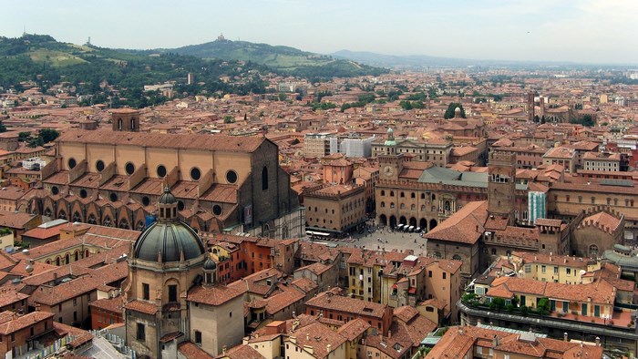 Aerial view of Bologna cityscape with red roofs and hills