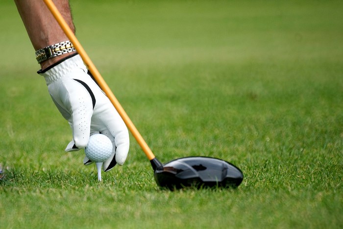Golfer placing ball on tee with driver