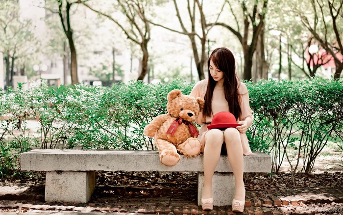 Asian girl with teddy bear and red hat in park