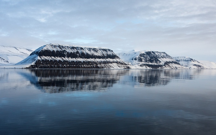 Snow-covered mountains reflected in calm water