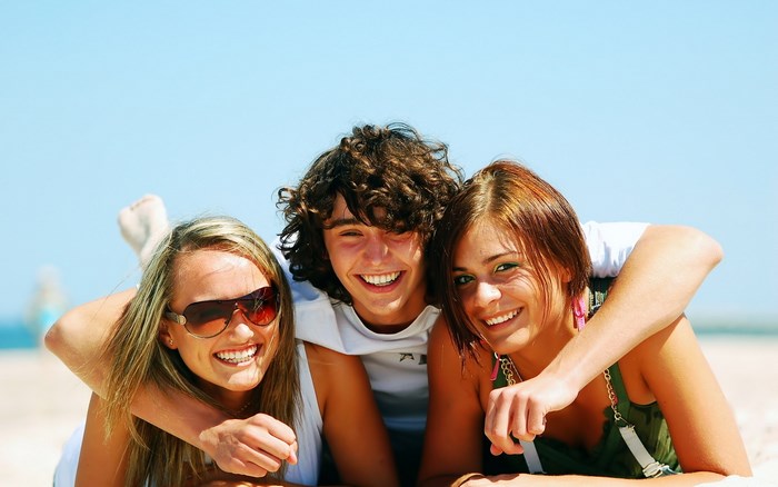 Three friends smiling on a beach