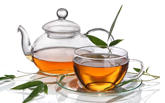 Glass teapot and cup of tea with bamboo leaves