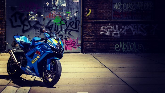 Blue Suzuki GSX-R motorcycle parked in front of graffiti wall