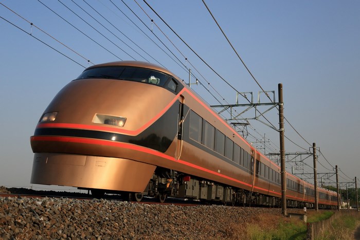 Golden train with red stripe on tracks