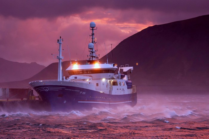 Fishing boat in rough seas at sunset