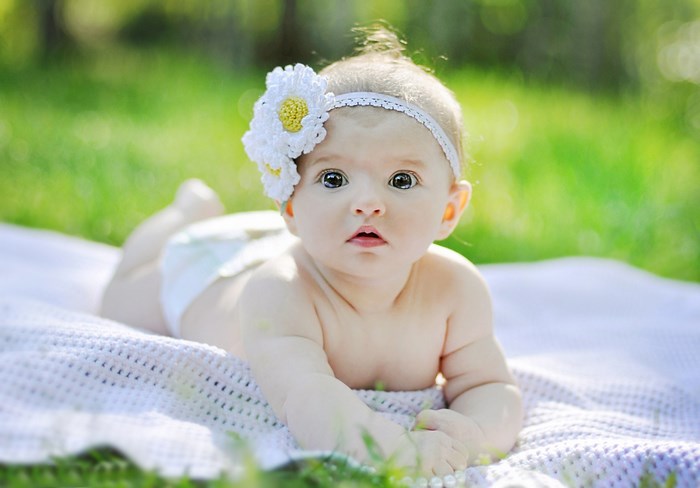 Baby girl with flower headband on blanket