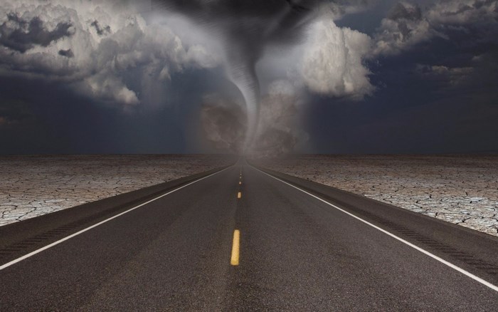 Tornado over a cracked desert landscape with a road