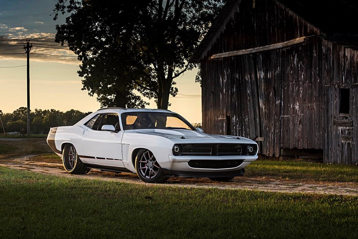 White Plymouth Barracuda parked near a barn
