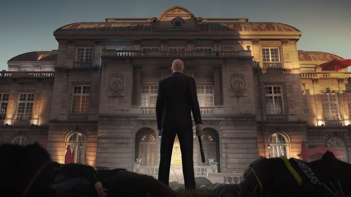Agent 47 from Hitman standing in front of a mansion