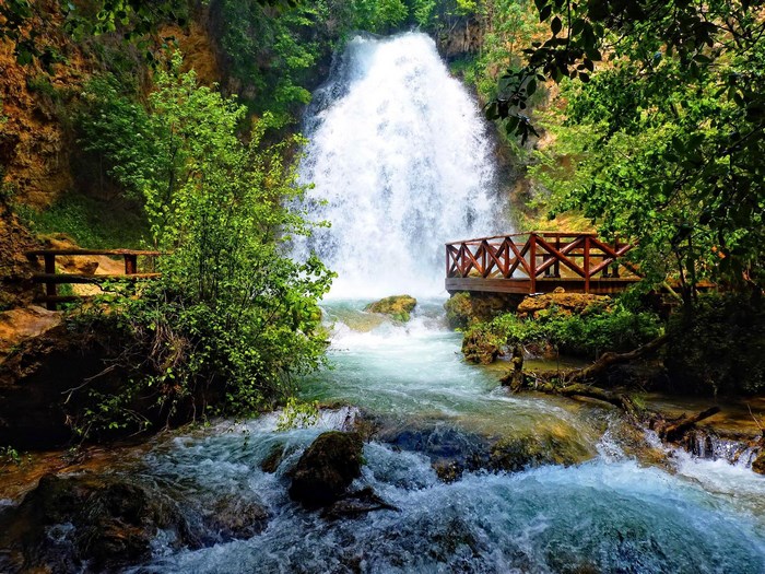 Waterfall with wooden viewing platforms and lush greenery