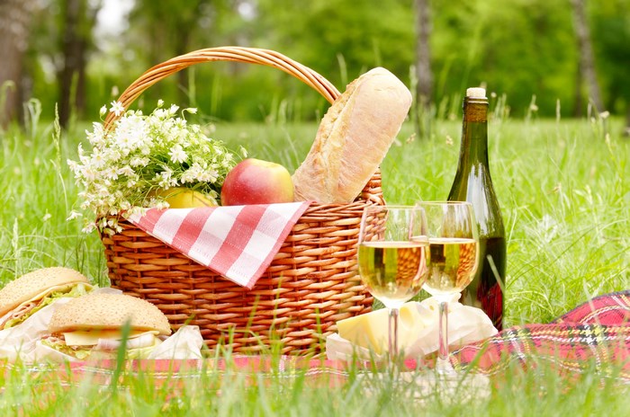 Picnic Basket with Bread, Fruits, and Wine Outdoors