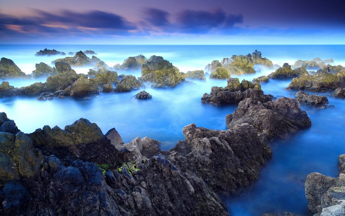 Rocky coastline with ocean waves at sunset