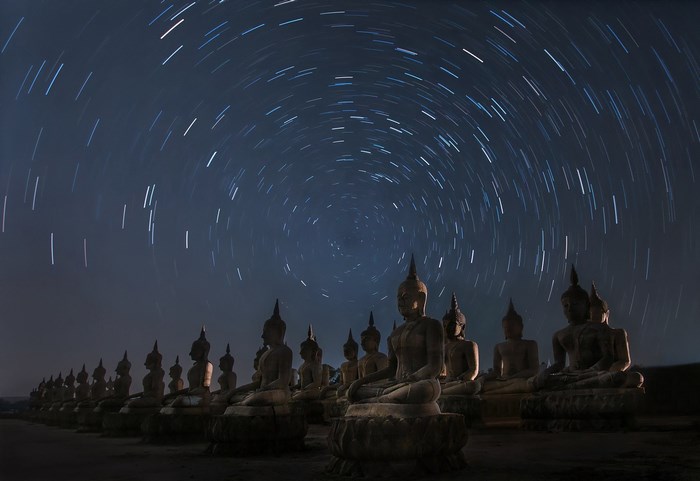 Buddha statues under star trails at night