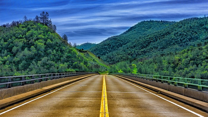 4K highway bridge through green mountains