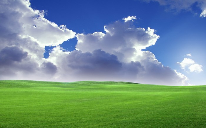Green rolling hills under a blue sky with clouds