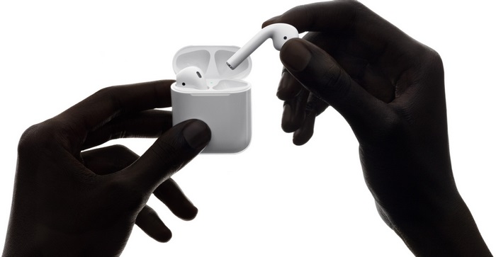 Hands holding Apple AirPods and charging case