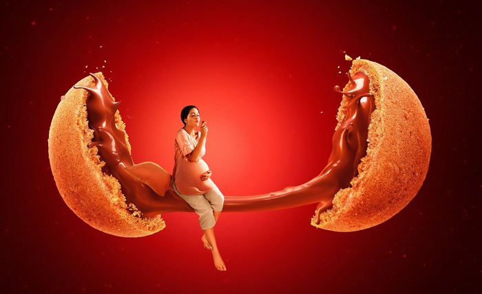 Pregnant woman eating chocolate from a broken cookie