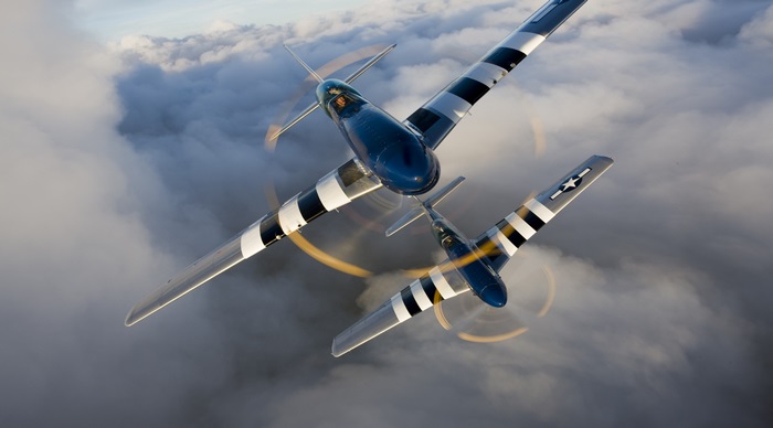 Two North American P-51 Mustangs flying through clouds