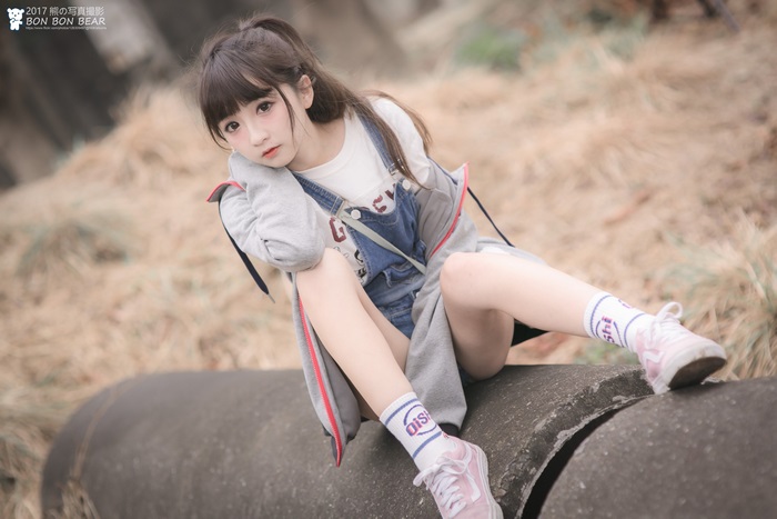Asian girl in overalls sitting on a pipe