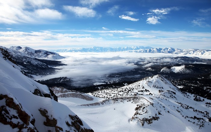 Snowy mountain range with clouds and blue sky