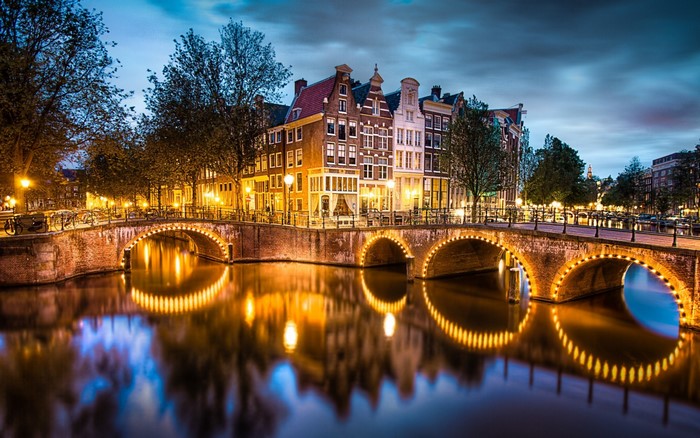 Illuminated Bridge and Canal in Amsterdam at Dusk