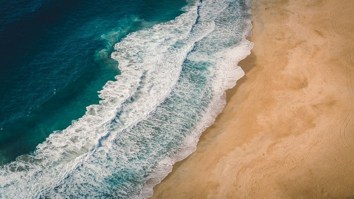 Aerial view of waves crashing on a sandy beach