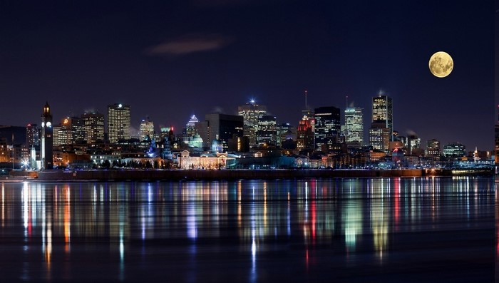 Montreal cityscape at night with full moon over river