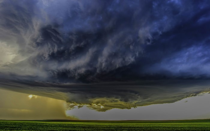 Supercell storm clouds over a green field