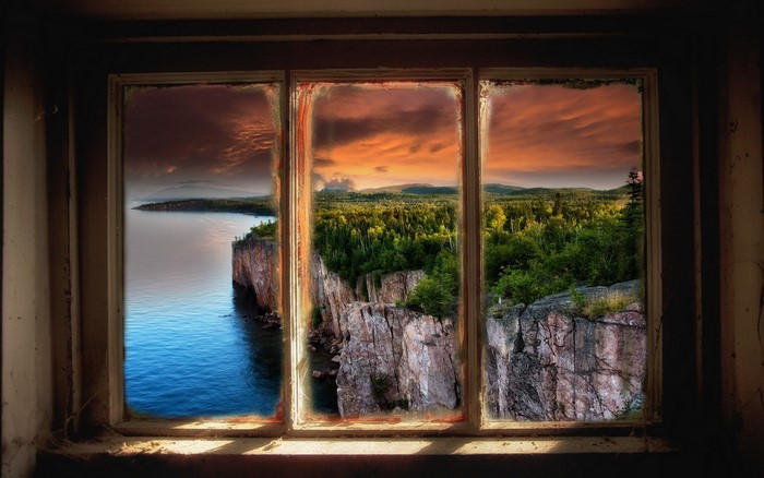 Cliffside forest and lake view through a window at sunset