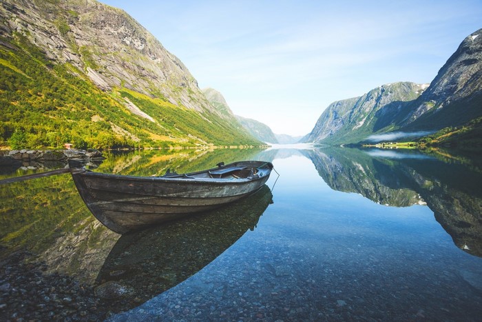 Boat on a calm lake with mountains and reflections