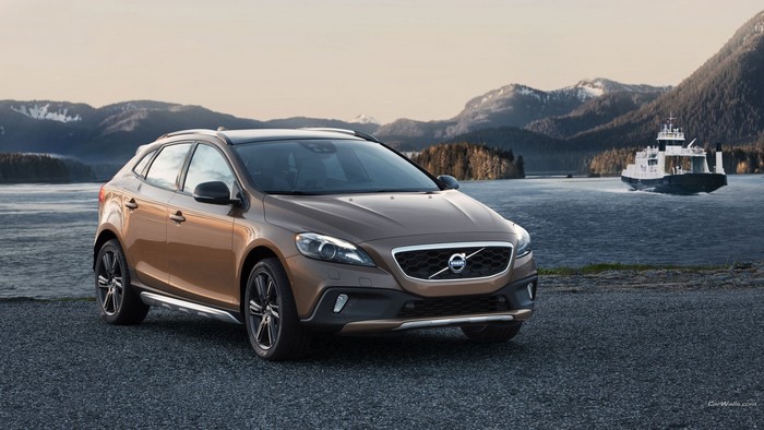 Volvo V40 Cross Country parked by a lake with mountains and a ferry