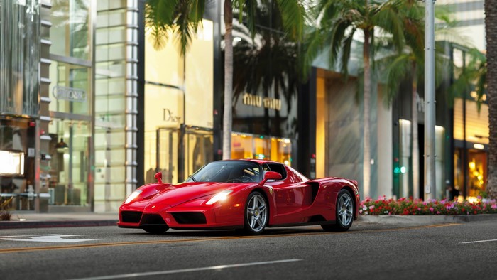 Red Ferrari Enzo on a Street with Palm Trees and Shops