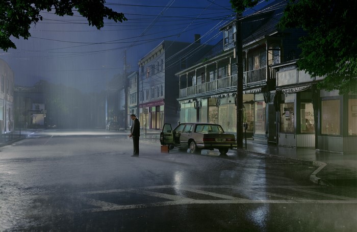 Man in suit by car on rainy city street at night