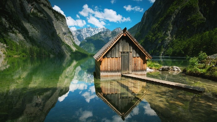 Wooden cabin on a lake with mountains