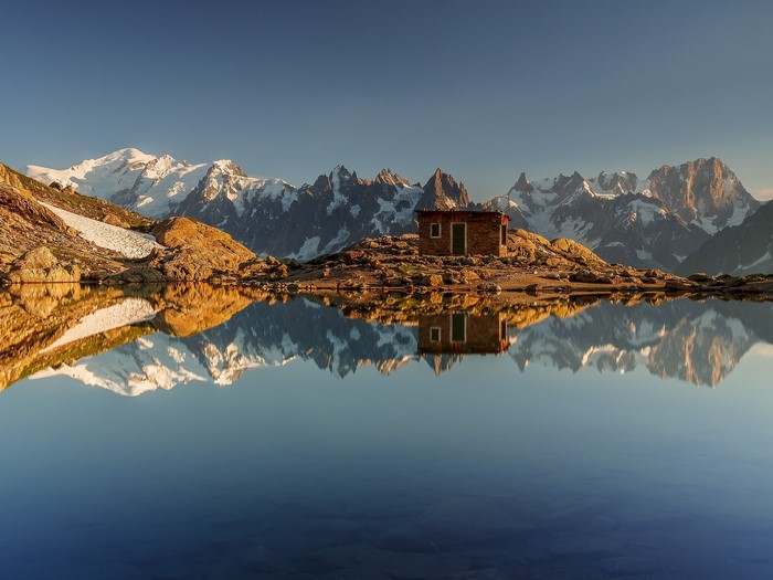Mountain lake reflection with stone hut and Chamonix mountains