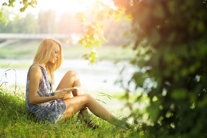 Woman reading a book by a lake