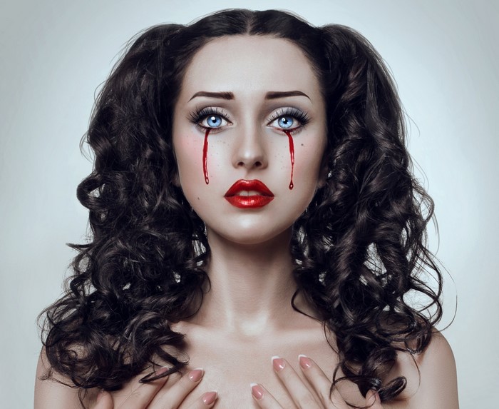 Woman with bloody tears and dark curly hair
