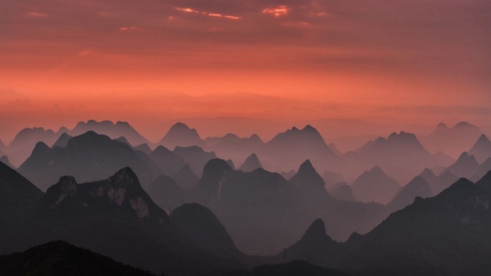 Mountains in mist during sunrise with pink sky