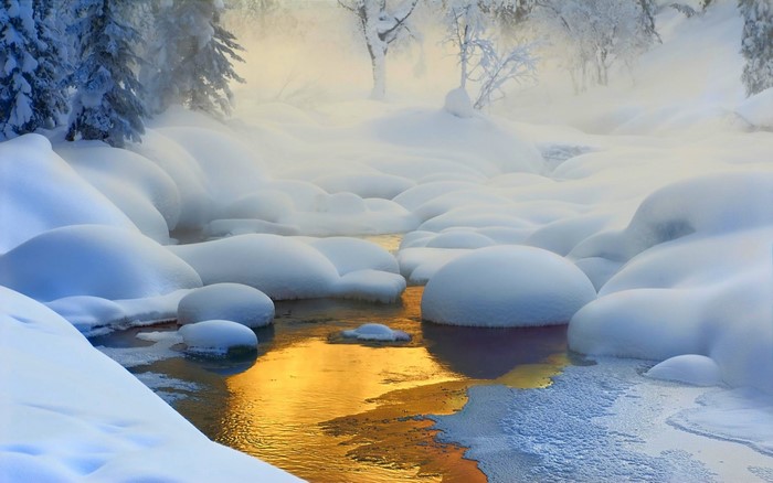 Snowy creek with golden water reflection and mist